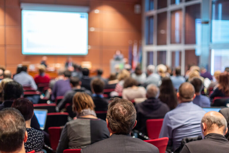 Audience in lecture hall participating at business event.